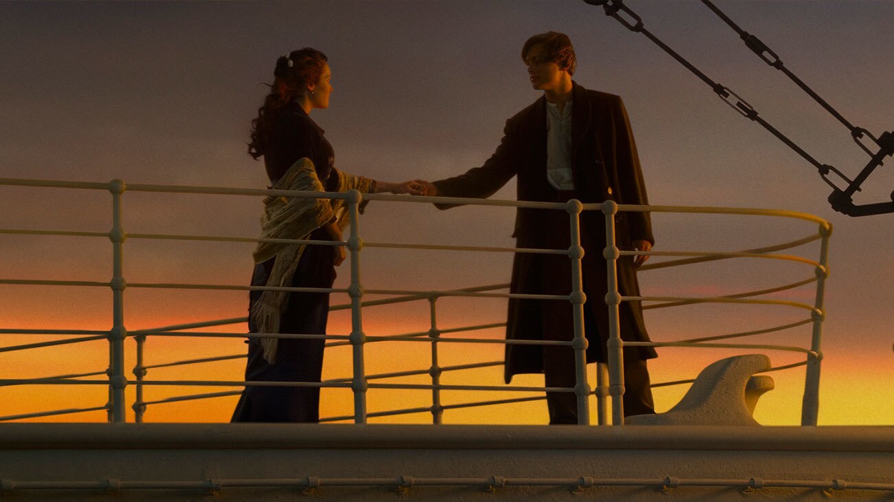 Titanic (1997) — Rose and Jack at the bow in sunset light Titanic (1997): Rose and Jack hold hands beside the ship’s bow railings against an orange sunset