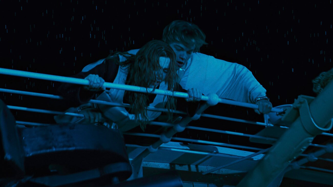 Titanic (1997) — Rose and Jack hold on during the sinking Titanic (1997): wet-haired Rose and Jack cling together behind white ship railings in blue night light